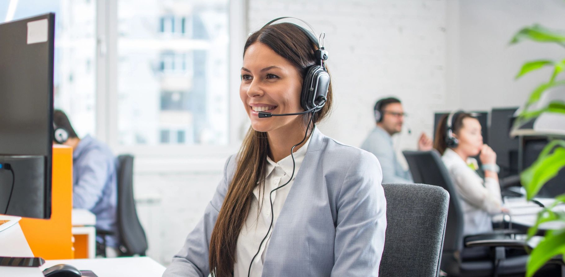 A support agent wearing a headset takes a call at her desk